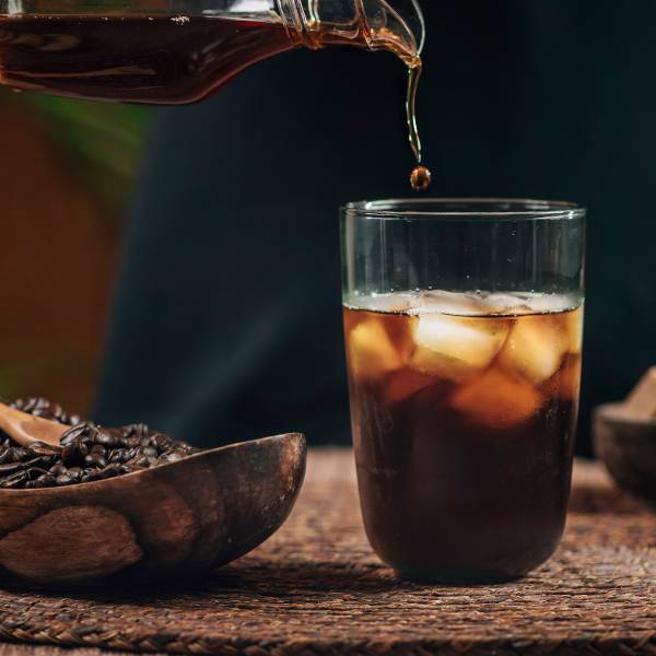 cold brew coffee being poured into glass of ice